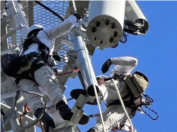 鉄塔の上で従業員が協力して作業をしています